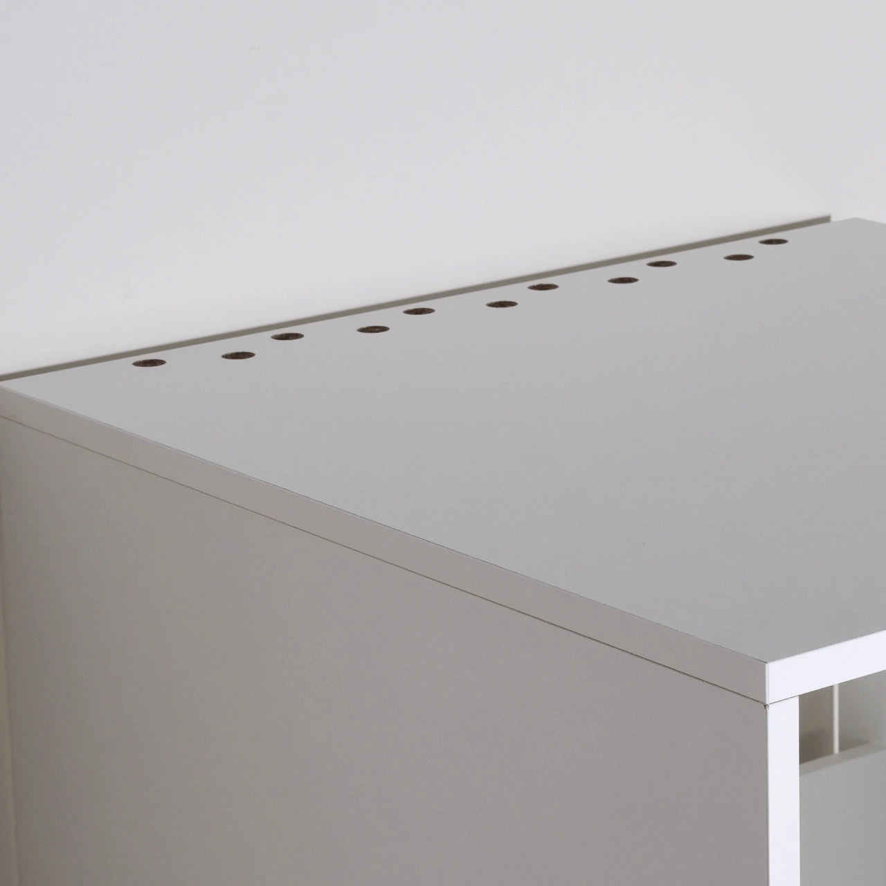 Metal drawer slide rail and white wooden cabinet corner with mounting bolt on wood floor background.
