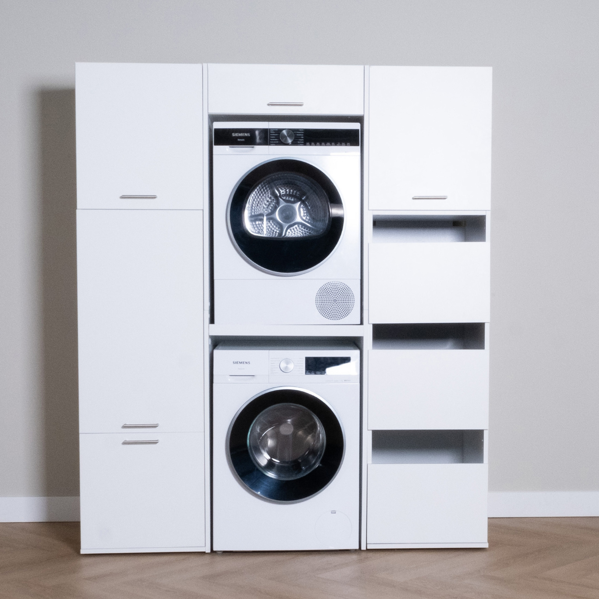 White modular laundry storage unit with front-loading washer and dryer stack, multiple cabinets and open shelves.